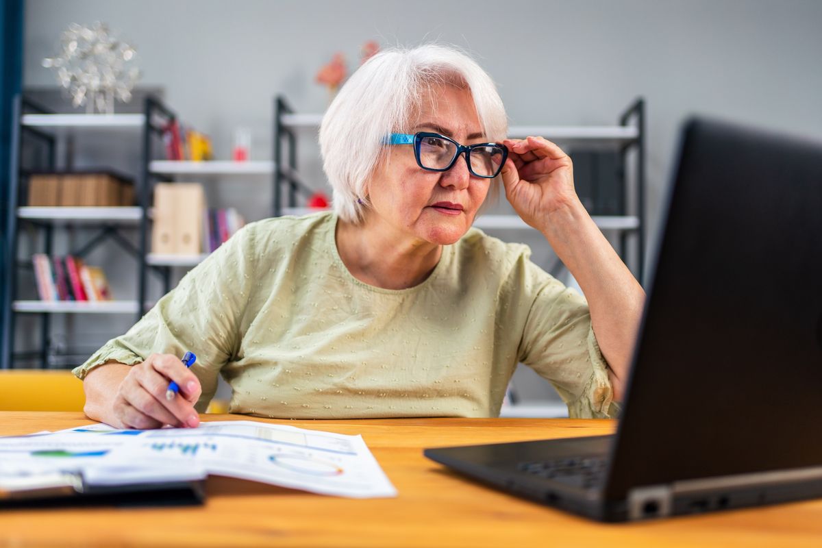 Pensioner looks at laptop while sorting finances