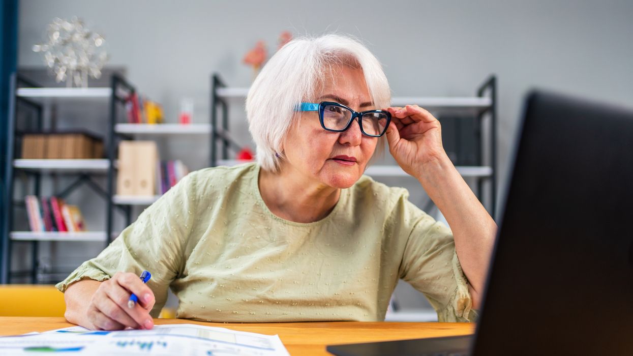 Pensioner looks at laptop while sorting finances