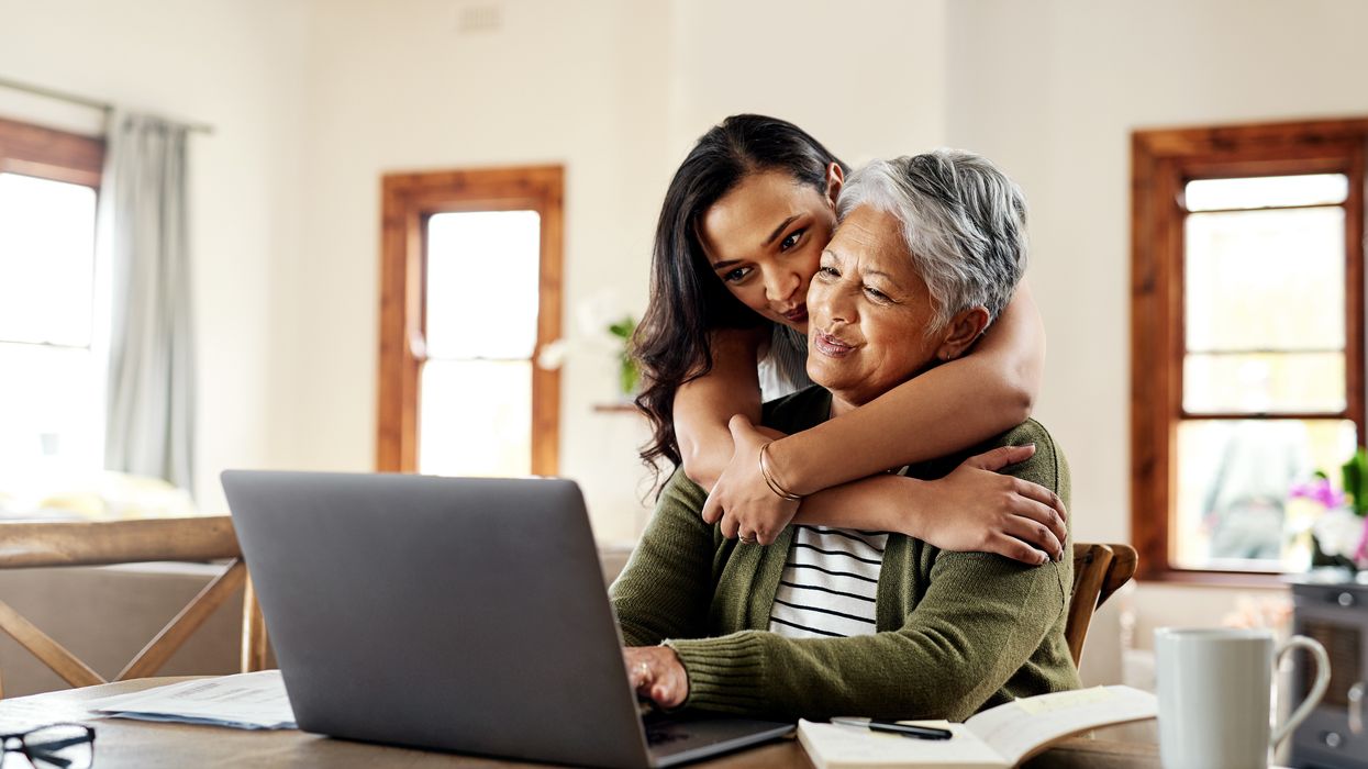 Pensioner looks at laptop with younger relative