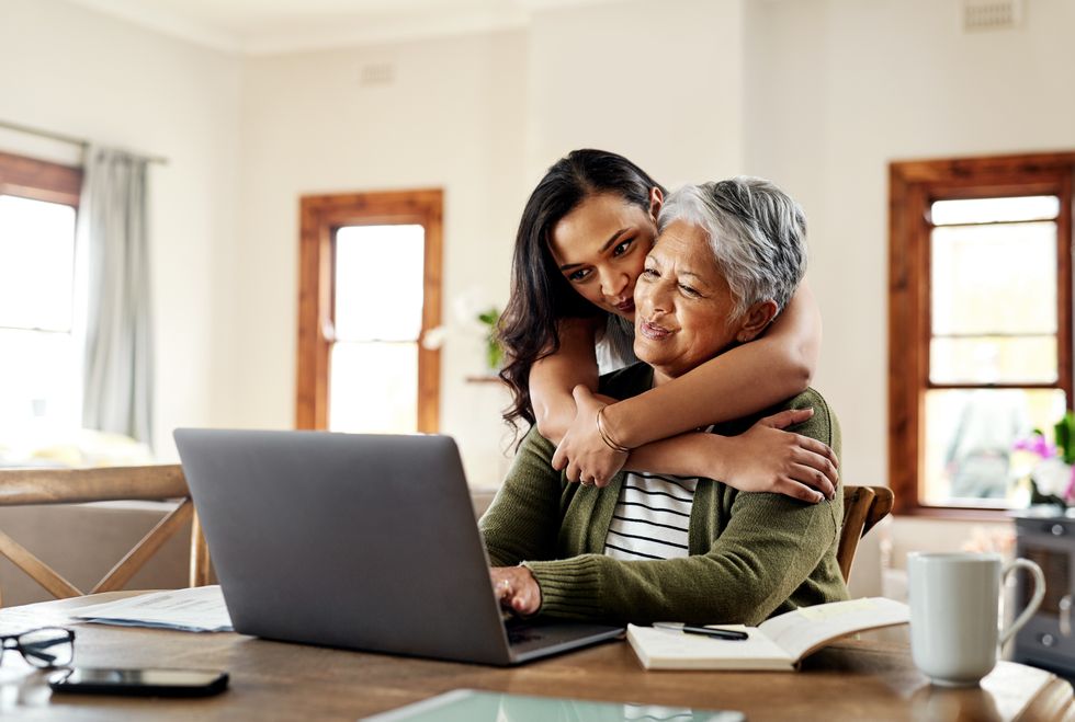 Pensioner looks at laptop with younger relative