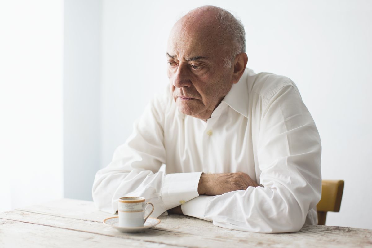 Pensioner looks unhappy while sitting with coffee at table