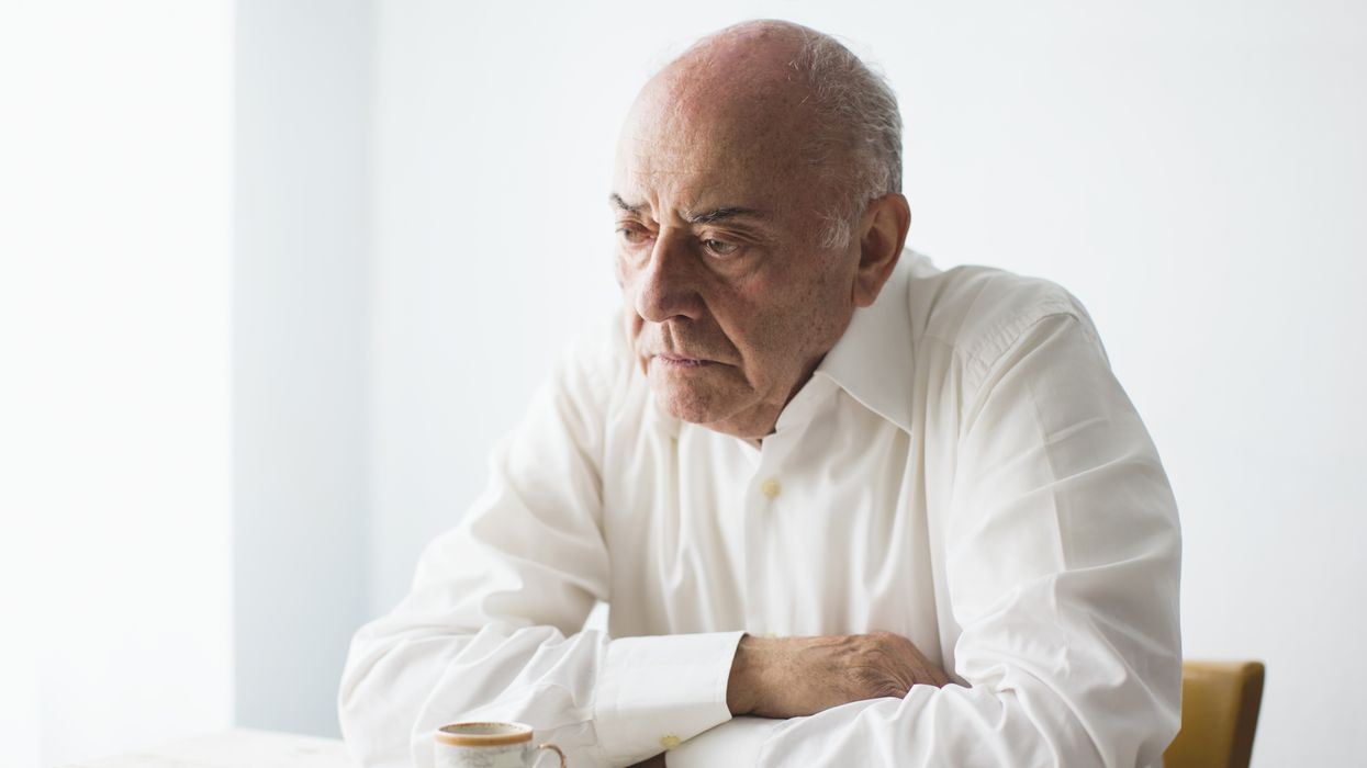 Pensioner looks unhappy while sitting with coffee at table