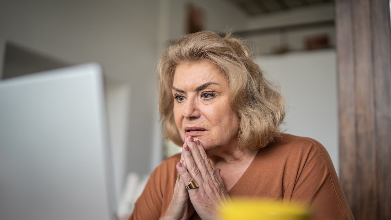 Pensioner looks worried at laptop