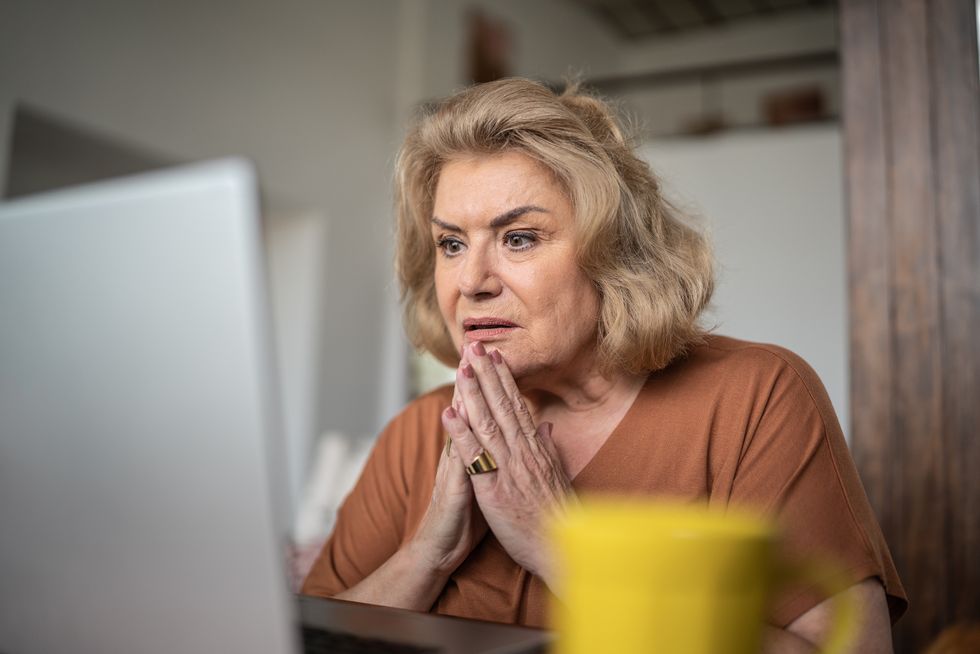 Pensioner looks worried at laptop