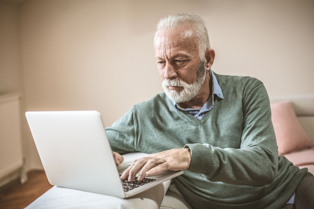 Pensioner looks worried at laptop