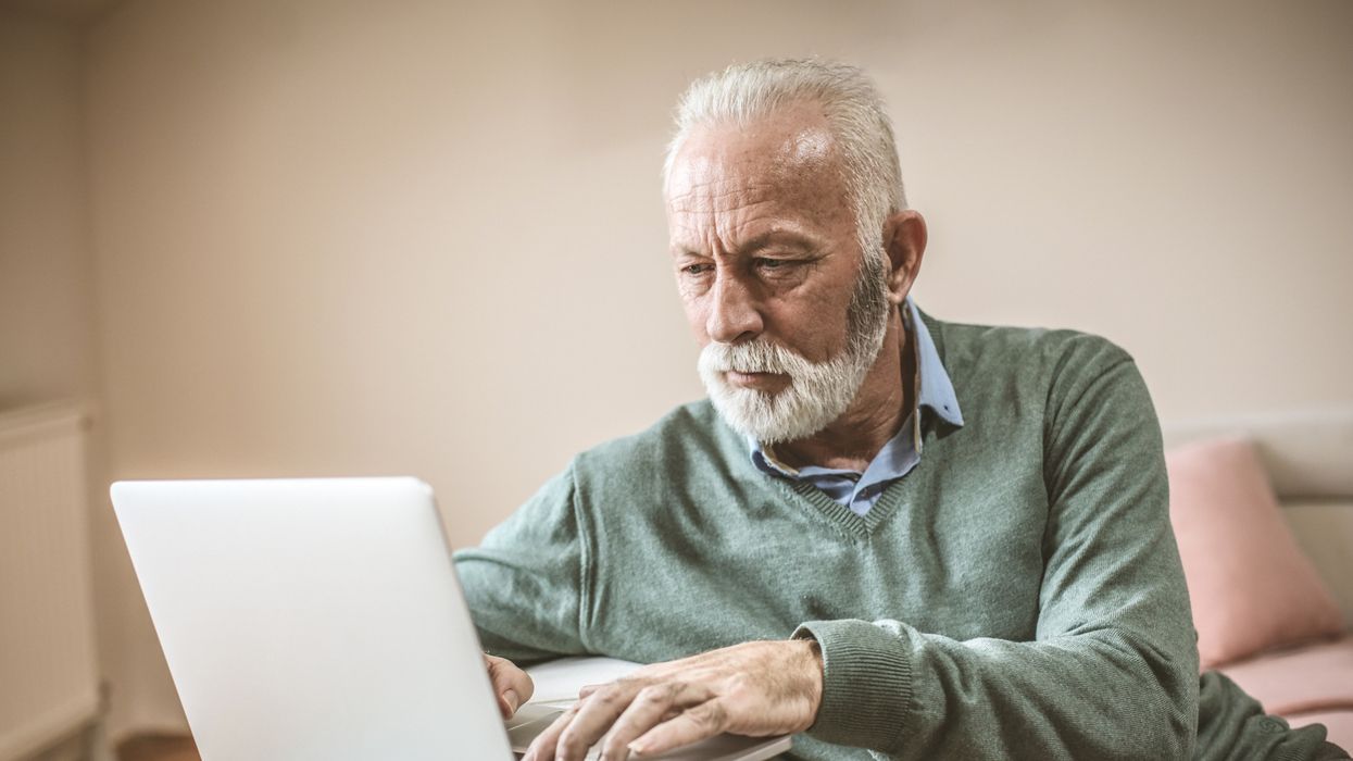 Pensioner looks worried at laptop
