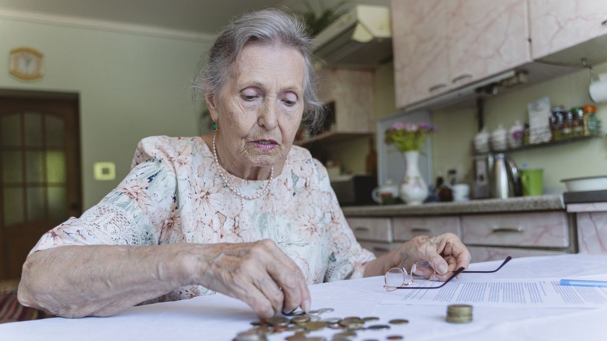 Pensioner looks worried while counting money at kitchen table