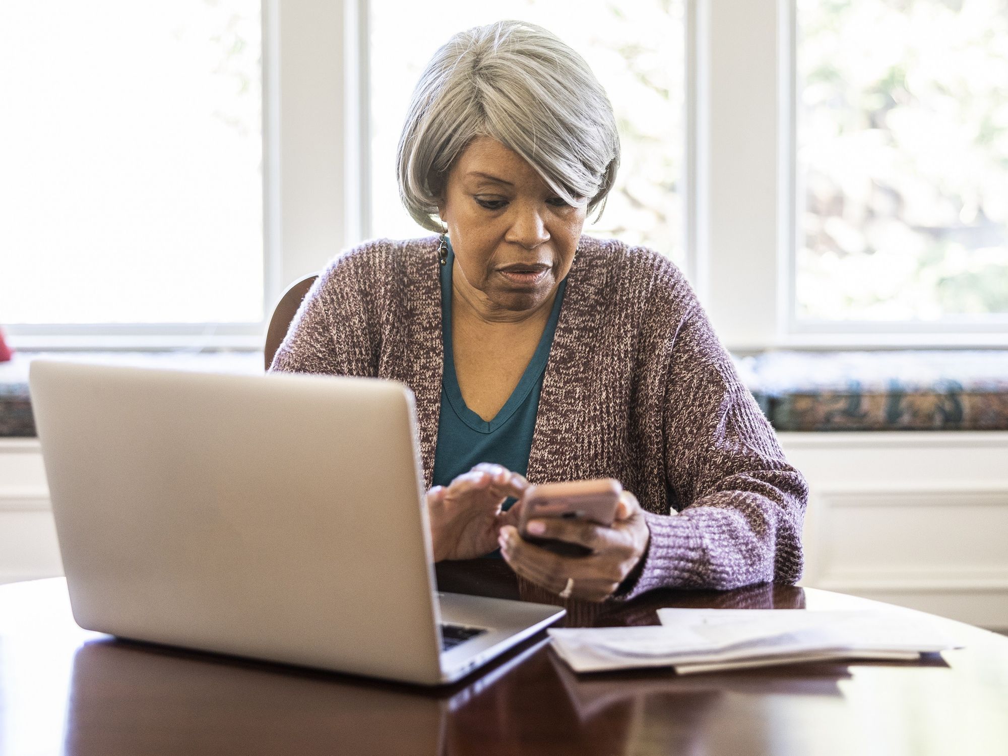Pensioner on phone in front of laptop