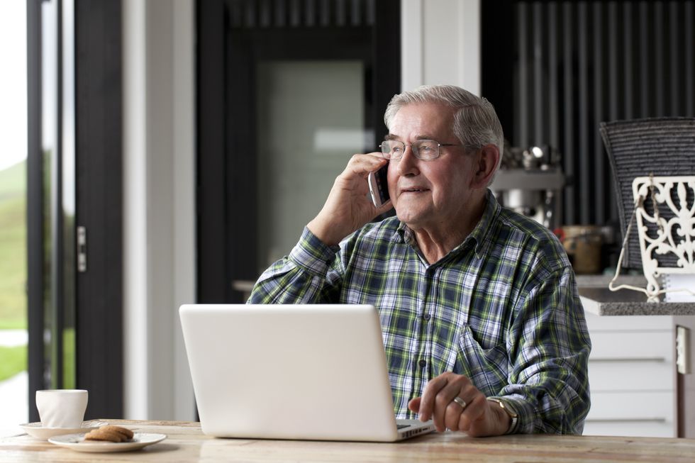 Pensioner on phone in front of laptop