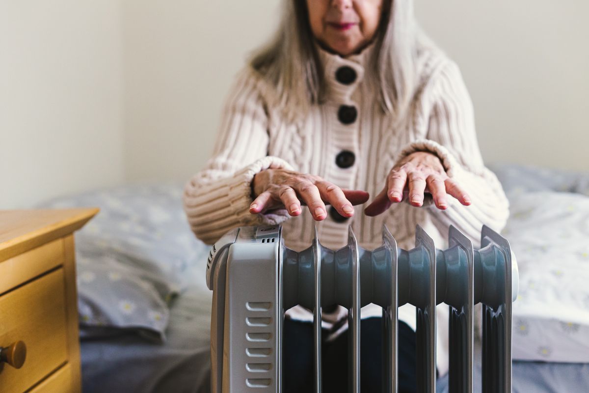 Pensioner sits by electric heater