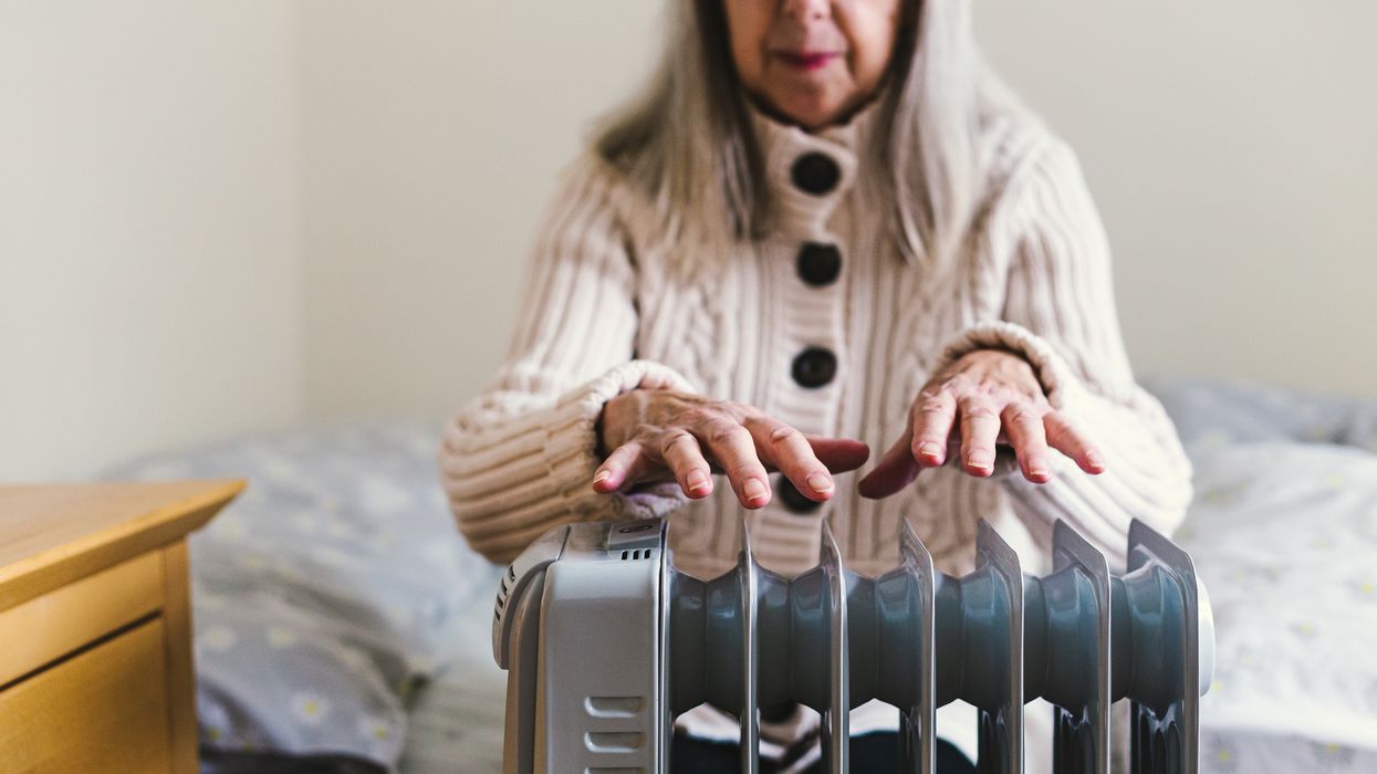Pensioner sits by electric heater
