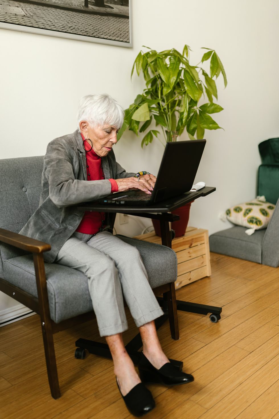 Pensioner types on laptop while sitting on chair