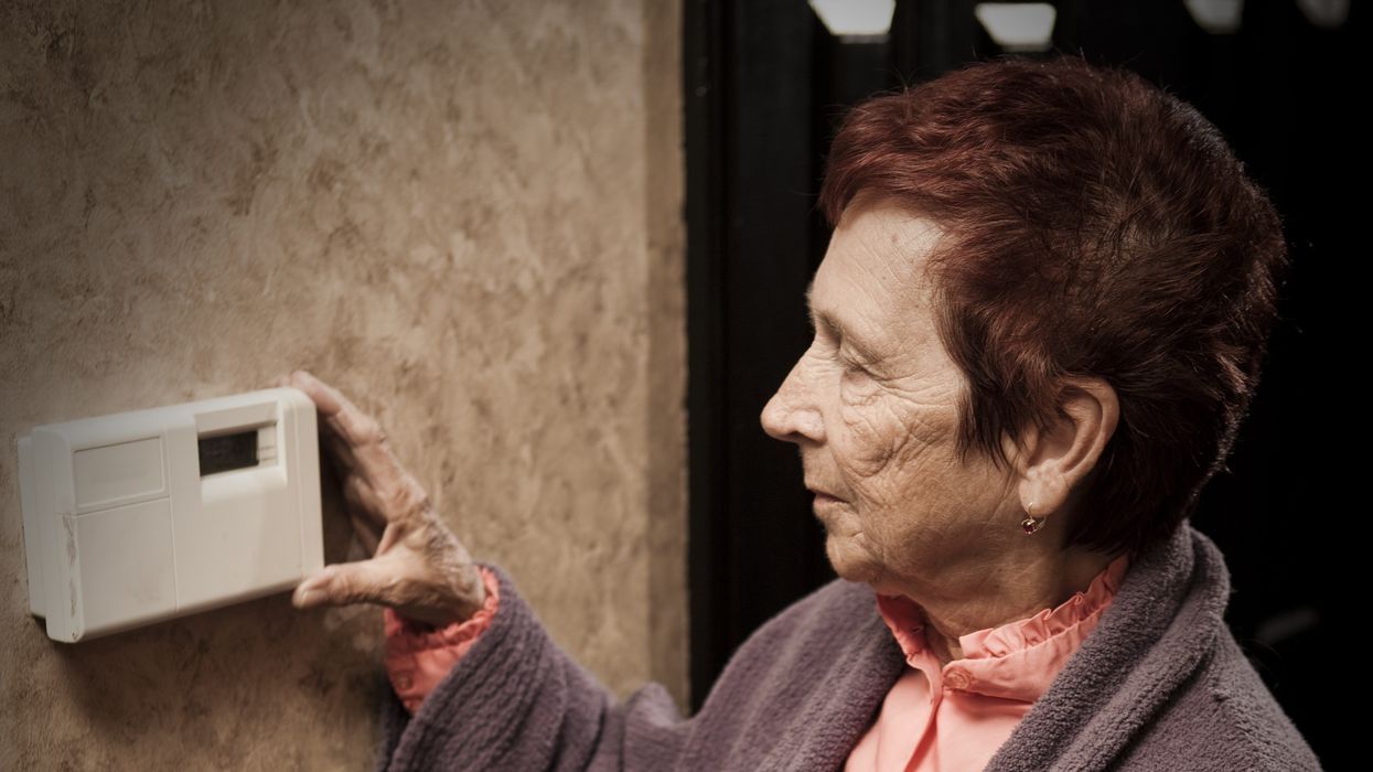 Pensioner with energy bills looks at thermostat