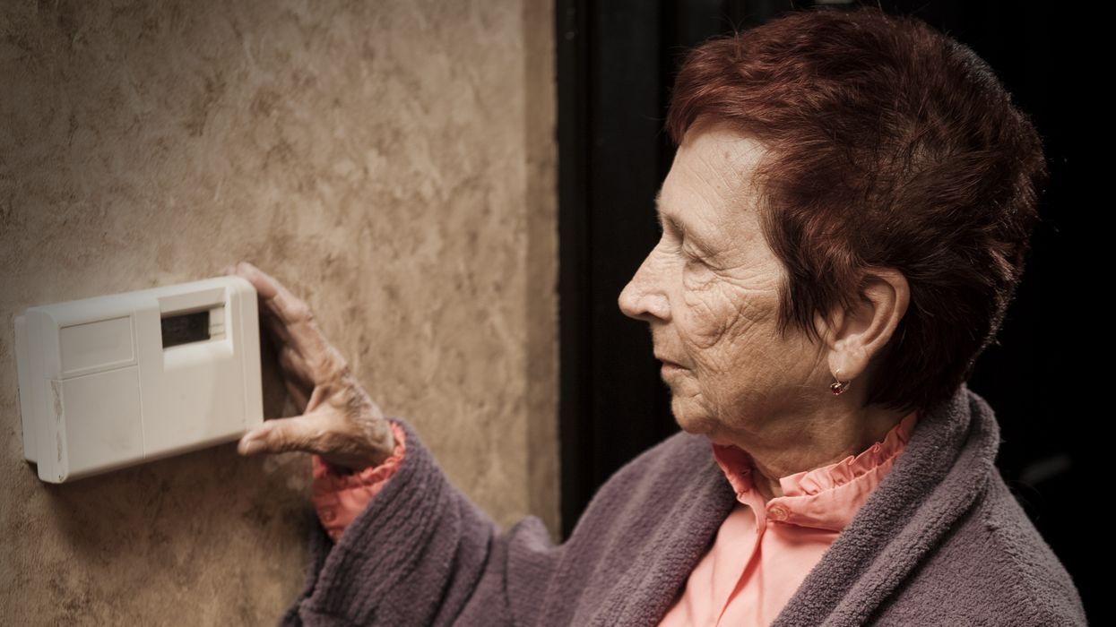 Pensioner with energy bills looks at thermostat