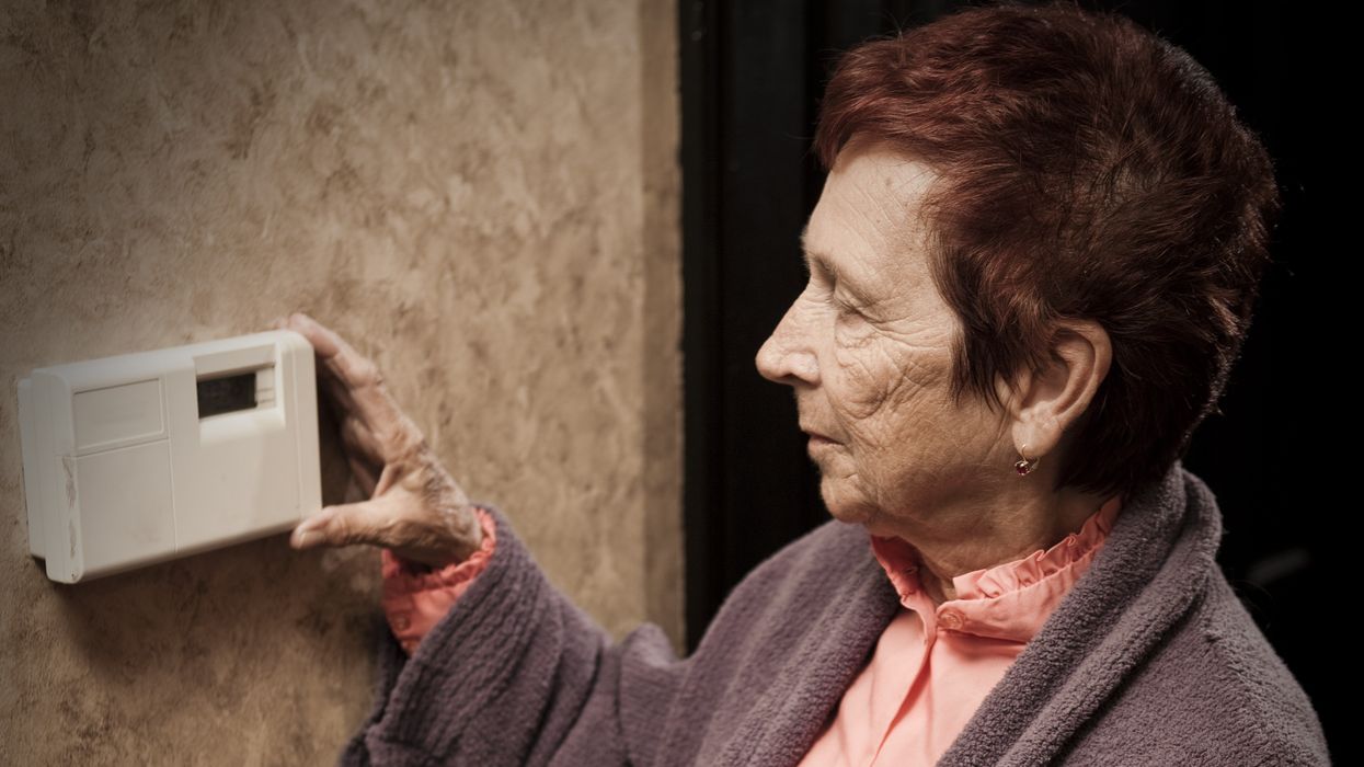 Pensioner with energy bills looks at thermostat