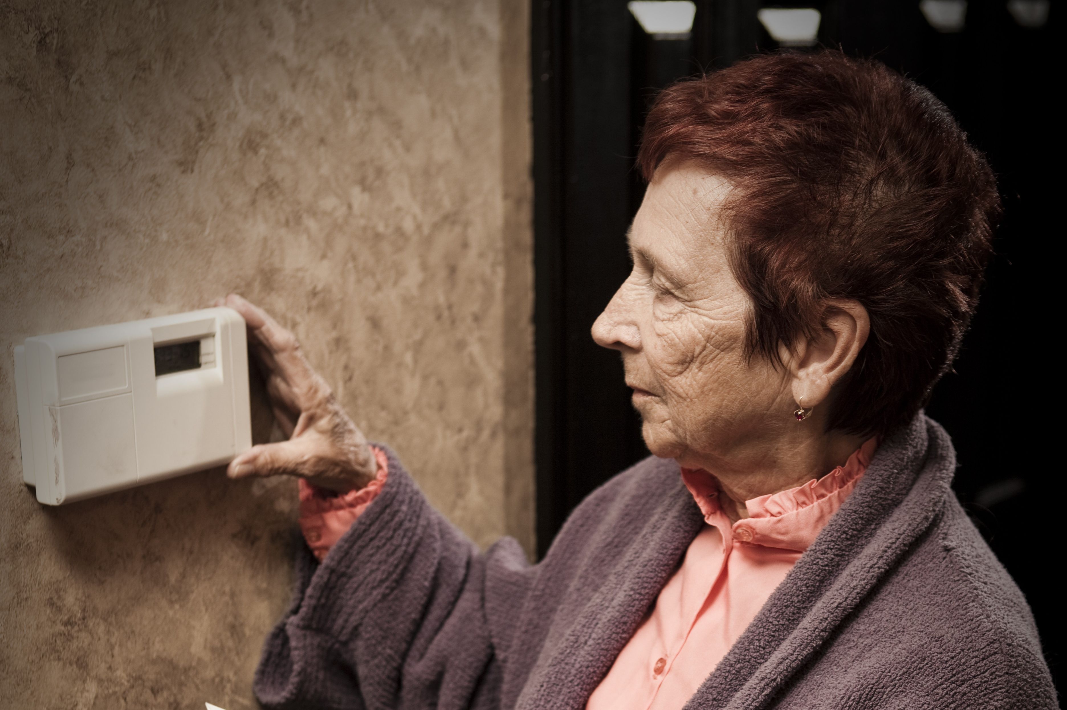 Pensioner with energy bills looks at thermostat