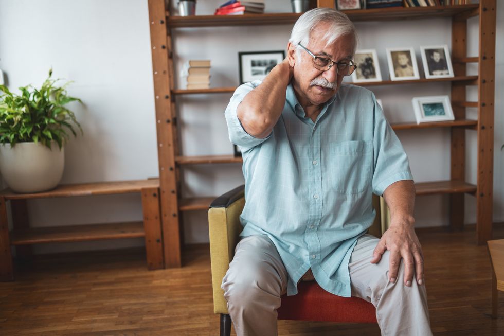 Pensioner with neck pain sits in chair