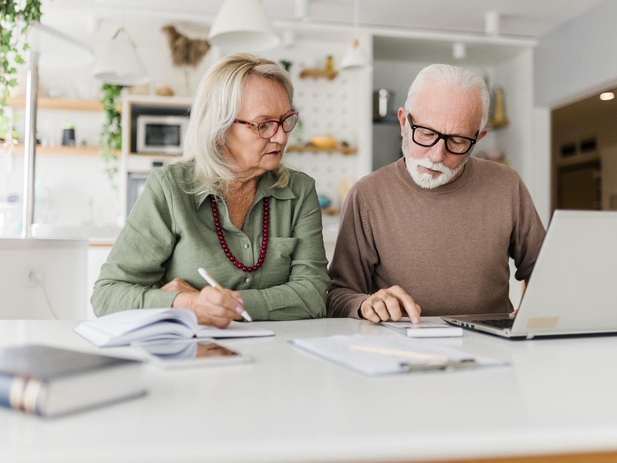 Pensioners look at calculator and laptop