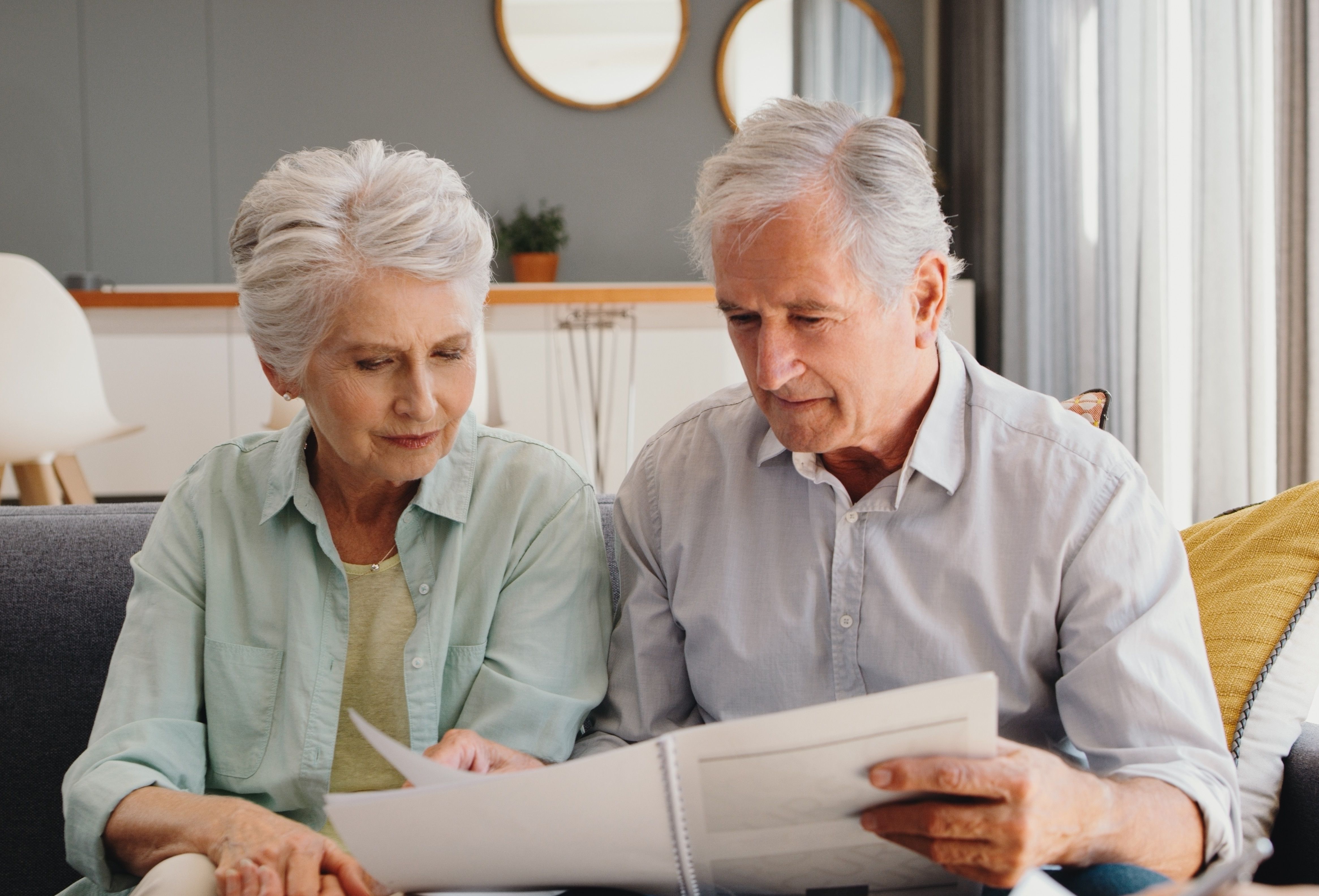 Pensioners look at document on sofa