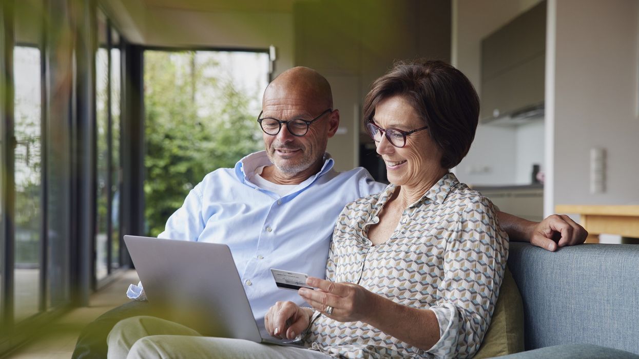 Pensioners look at finances with laptop and debit card
