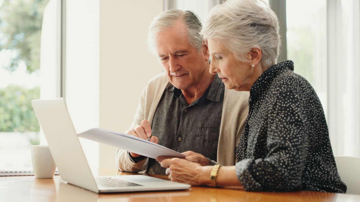 Pensioners look at finances with laptop and financial document