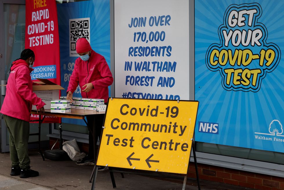 People arrange boxes at a free Covid-19 rapid lateral flow test kit handout point on Hoe Street in Walthamstow