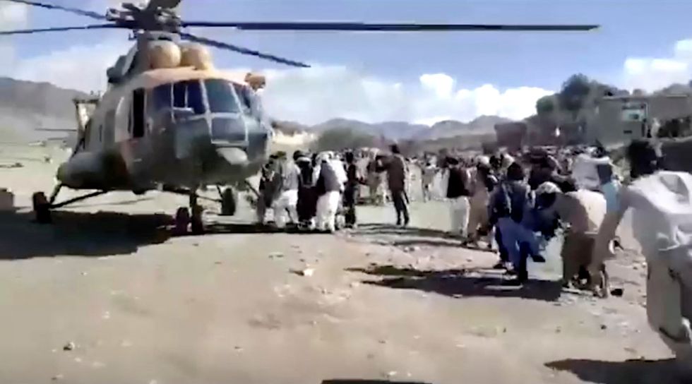 People carry injured to a helicopter following a massive earthquake, in Paktika Province, Afghanistan.