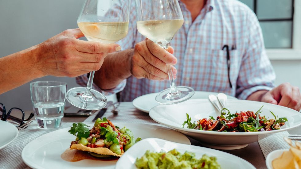 People clinking wine glasses while having dinner