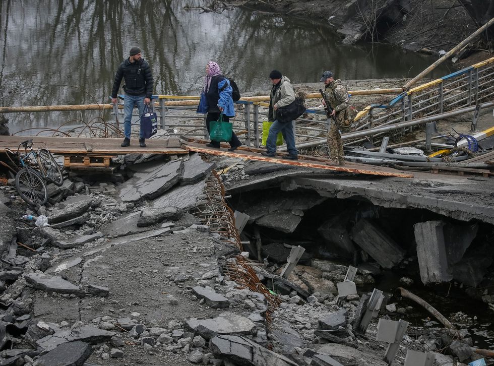 People cross the Irpin river near a destroyed bridge as they evacuate from Irpin town, amid Russia's invasion of Ukraine, outside of Kyiv, Ukraine April 1, 2022. REUTERS/Gleb Garanich