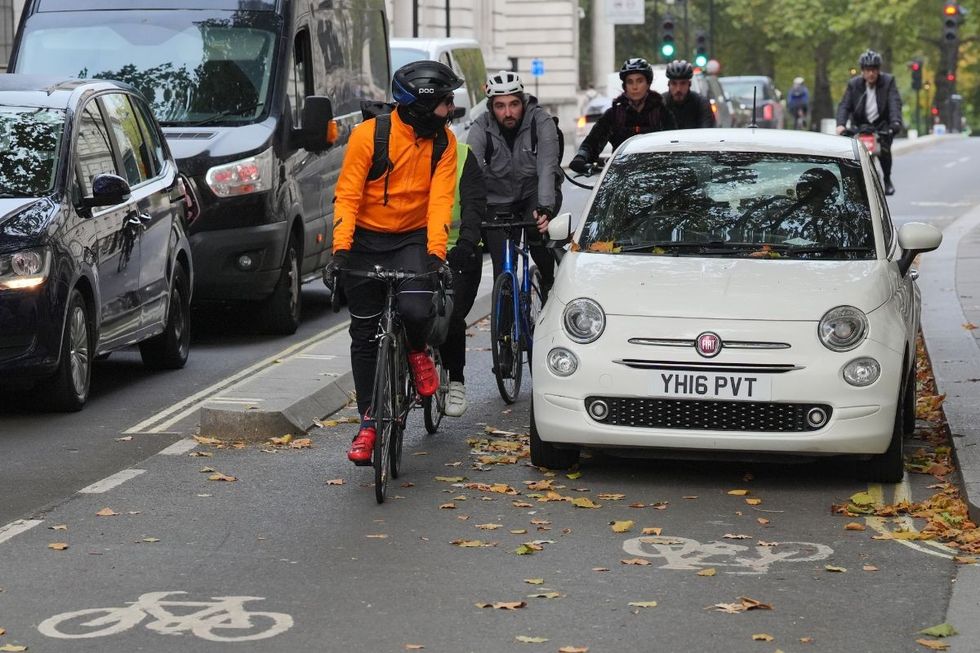 People cycling around a Fiat on a cycle lane