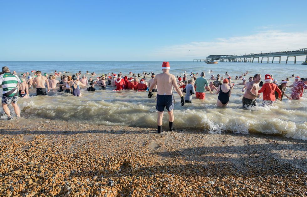 : People dressed in Santa hats and outfits for a festive swim
