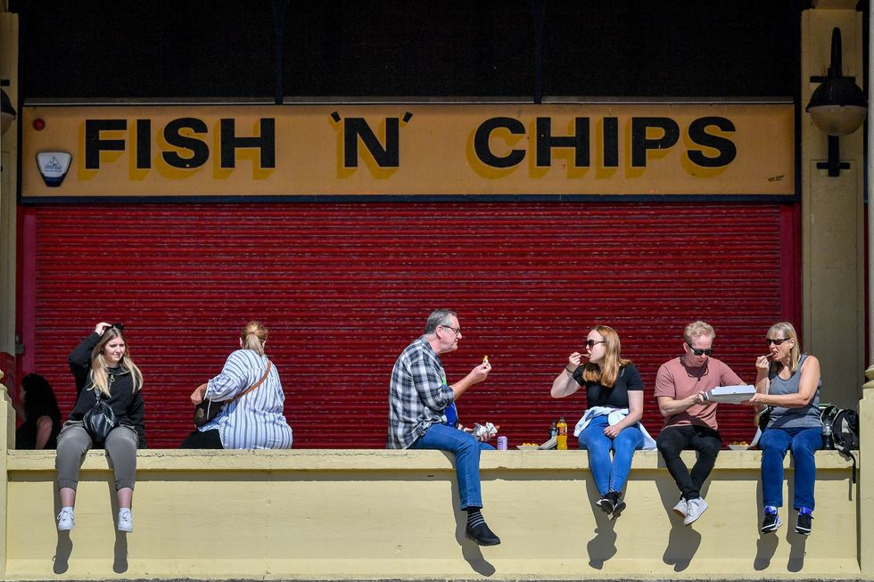 People eat fish and chips at Barry Island, Wales.
