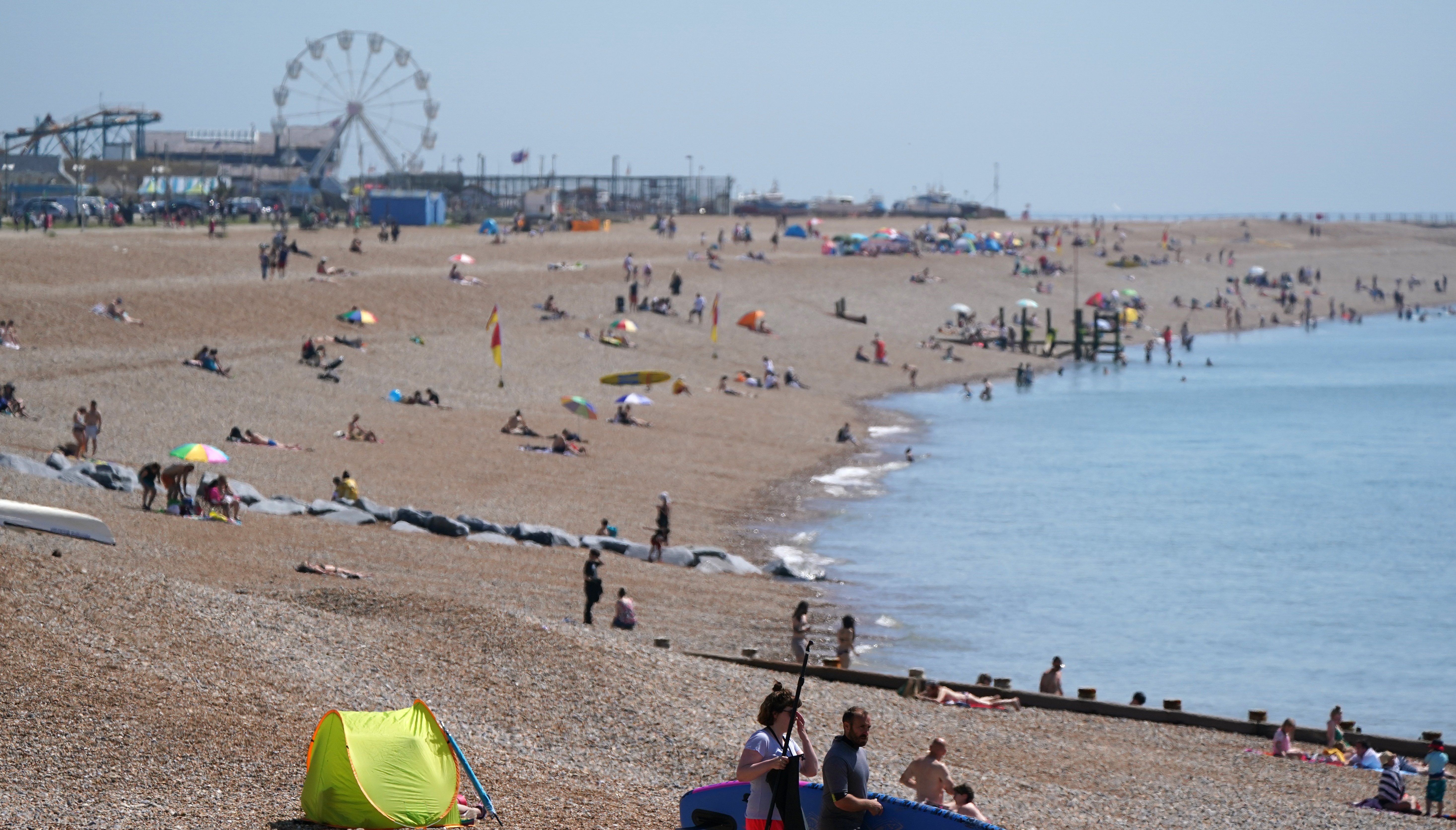 People enjoy the warm weather on Hastings beach in East Sussex - it's going to be another hot day on Monday.