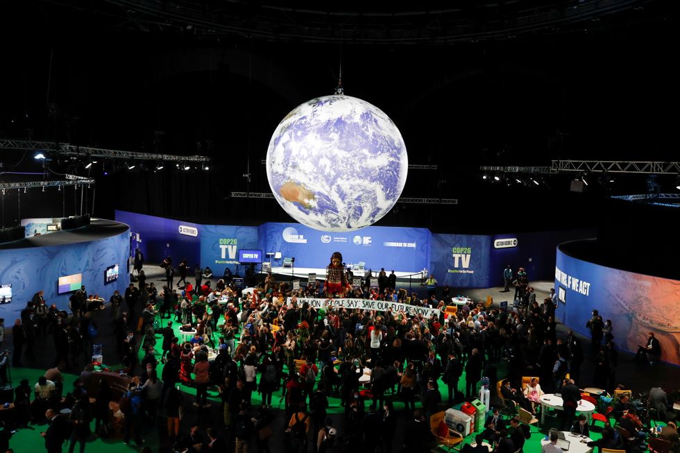 People gather around "Little Amal", a 3.5 metre tall puppet of a young Syrian refugee girl, during COP26