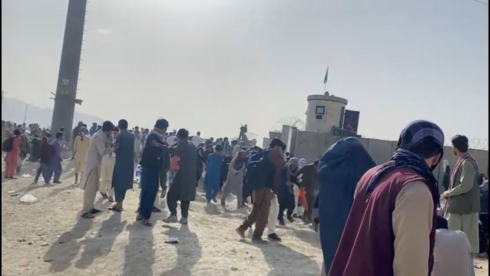People gathered outside the airport react to gunfire, in Kabul, Afghanistan August 18, 2021 in this still image taken from video.