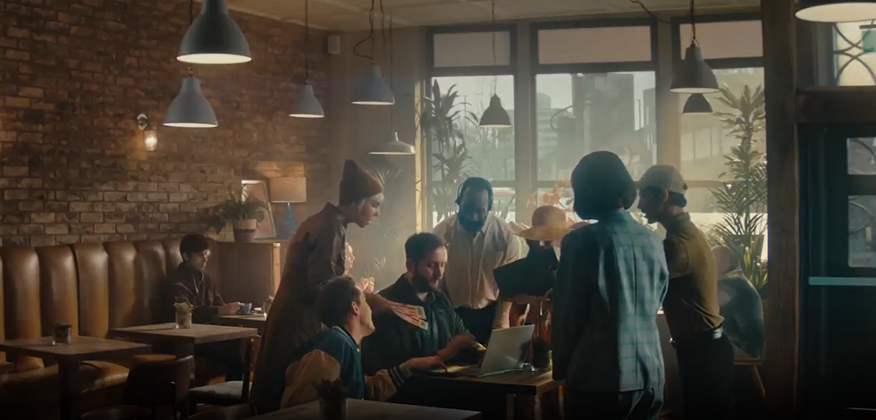 People gathered round man in cafe