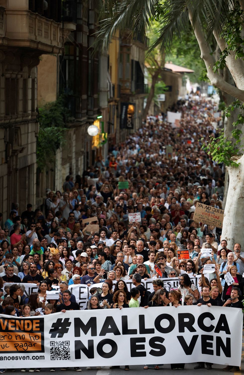 People hold a banner that reads "Mallorca is not for sale", as they take part in a protest against mass tourism and gentrification in the island