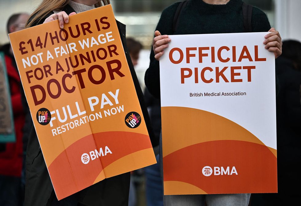 People hold British Medical Association (BMA) branded placards calling for better pay, as they stand on a picket line outside University College Hospital