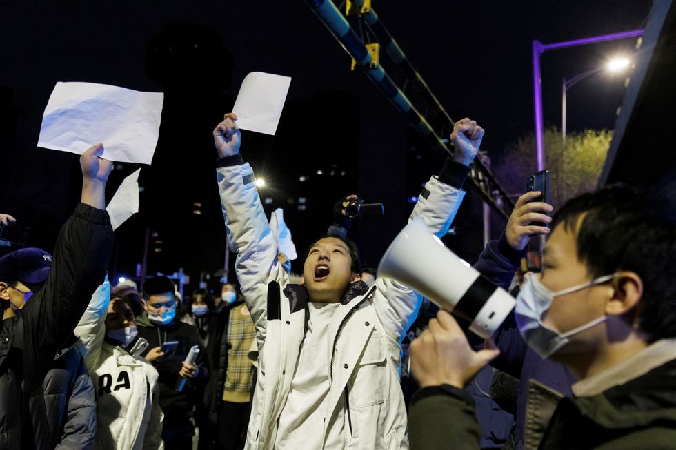 People hold white sheets of paper in protest over coronavirus disease (COVID-19) restrictions after a vigil for the victims of a fire in Urumqi, as outbreaks of COVID-19 continue, in Beijing, China, November 28, 2022. REUTERS/Thomas Peter