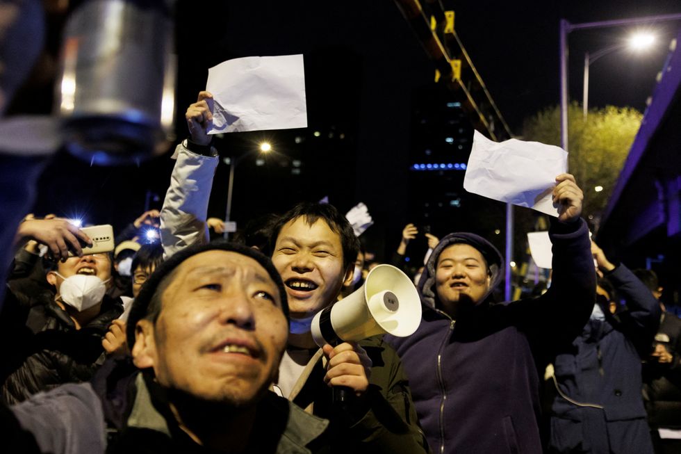 People hold white sheets of paper in protest over coronavirus disease (COVID-19) restrictions after a vigil for the victims of a fire in Urumqi, as outbreaks of COVID-19 continue in Beijing, China, November 28, 2022. REUTERS/Thomas Peter