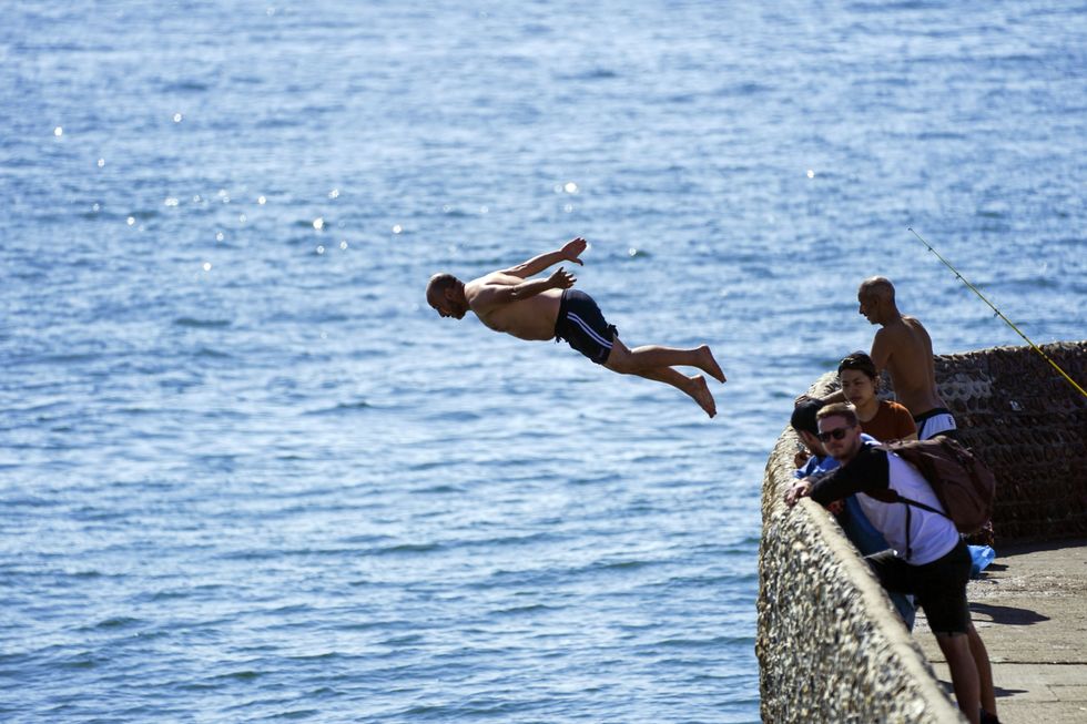People jump into the sea at Brighton beach in West Sussex. Temperatures are forecast to reach up to 30C in parts of the UK on Tuesday as the country enjoys a warm start to September. Picture date: Tuesday September 7, 2021.