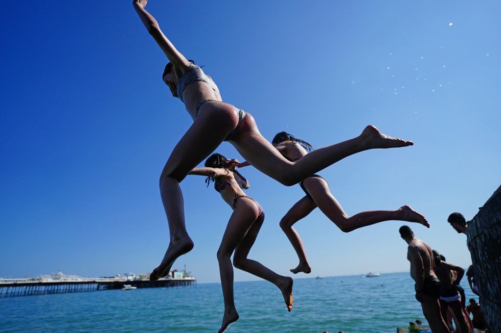 People jump into the sea from a groyne at Brighton beach in East Sussex.