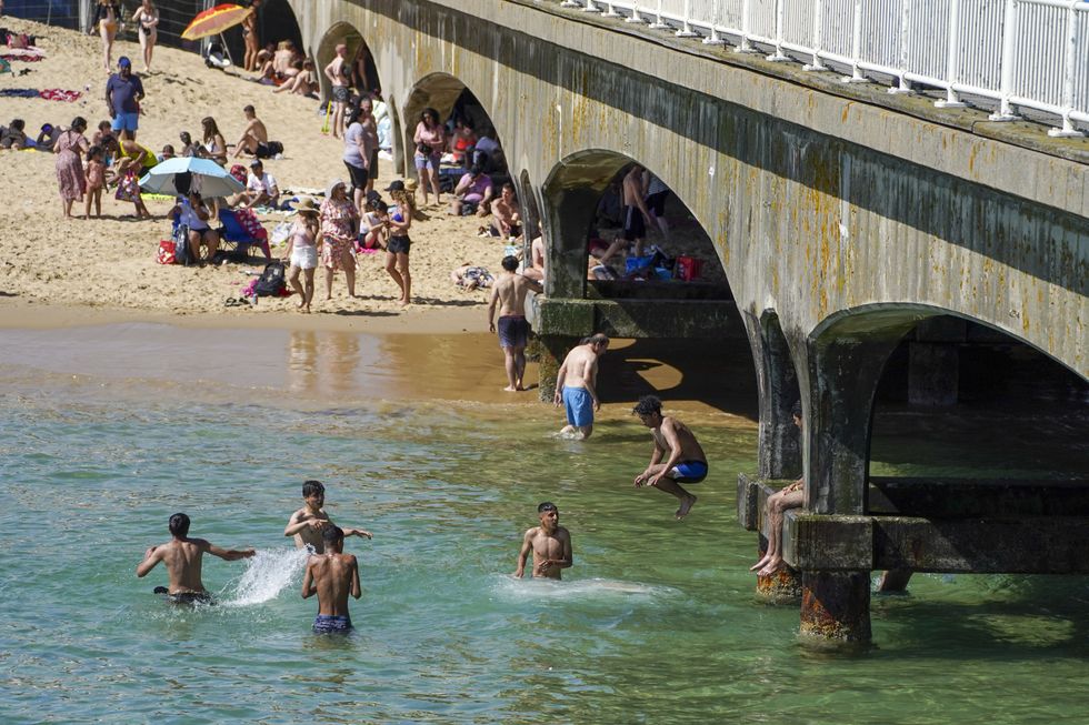 People jump off the pier as they enjoy the sea in Bournemouth, as the hot weather continues, with forecasters warning of the risk of thundery showers towards the end of the week.