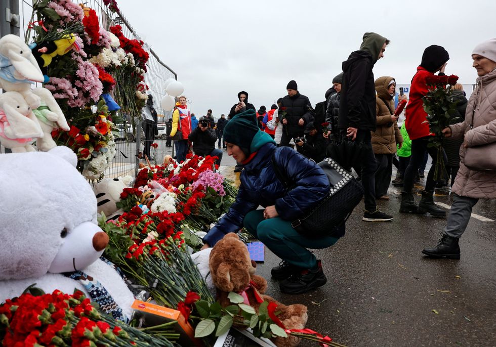 People lay flowers at a makeshift memorial to the victims of a shooting attack at the Crocus City Hill