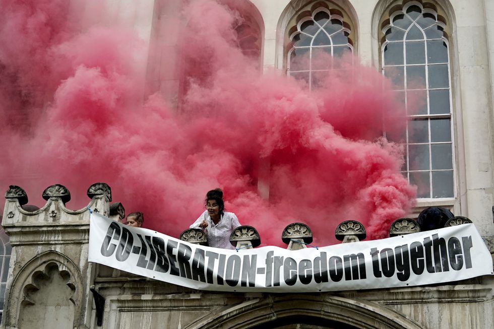 People let off flares and unfurl a banner from a ledge above the entrance to the Guildhall