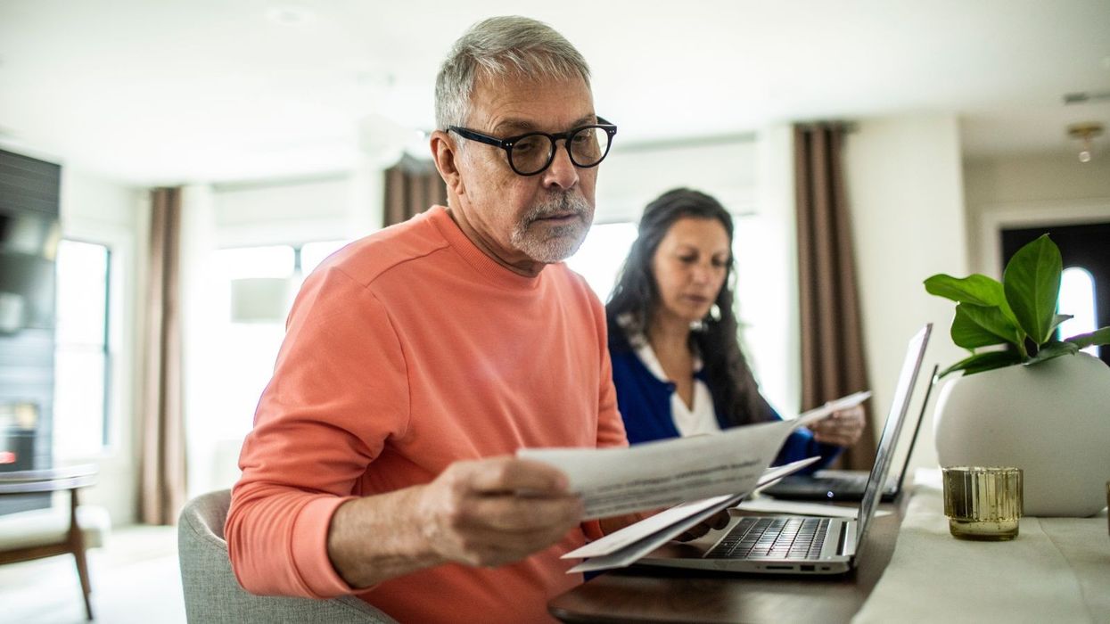 People look at finances on page in front of laptop