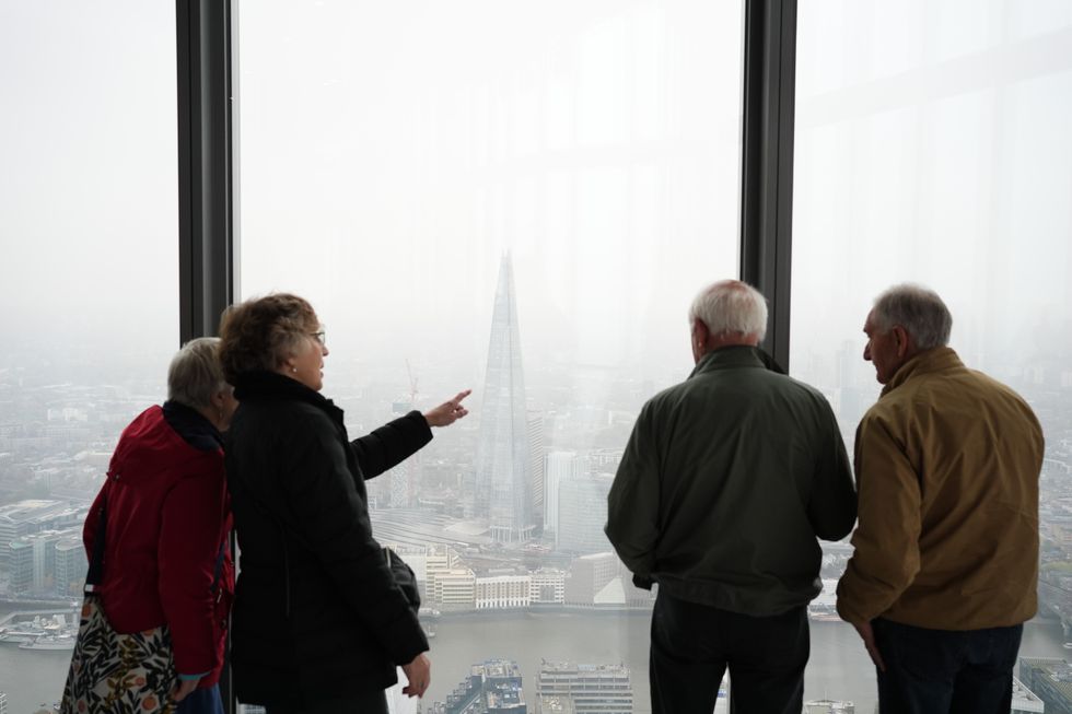 People look out from the viewing platform of Horizon 22 in Bishopsgate, London, as the sky is rendered grey