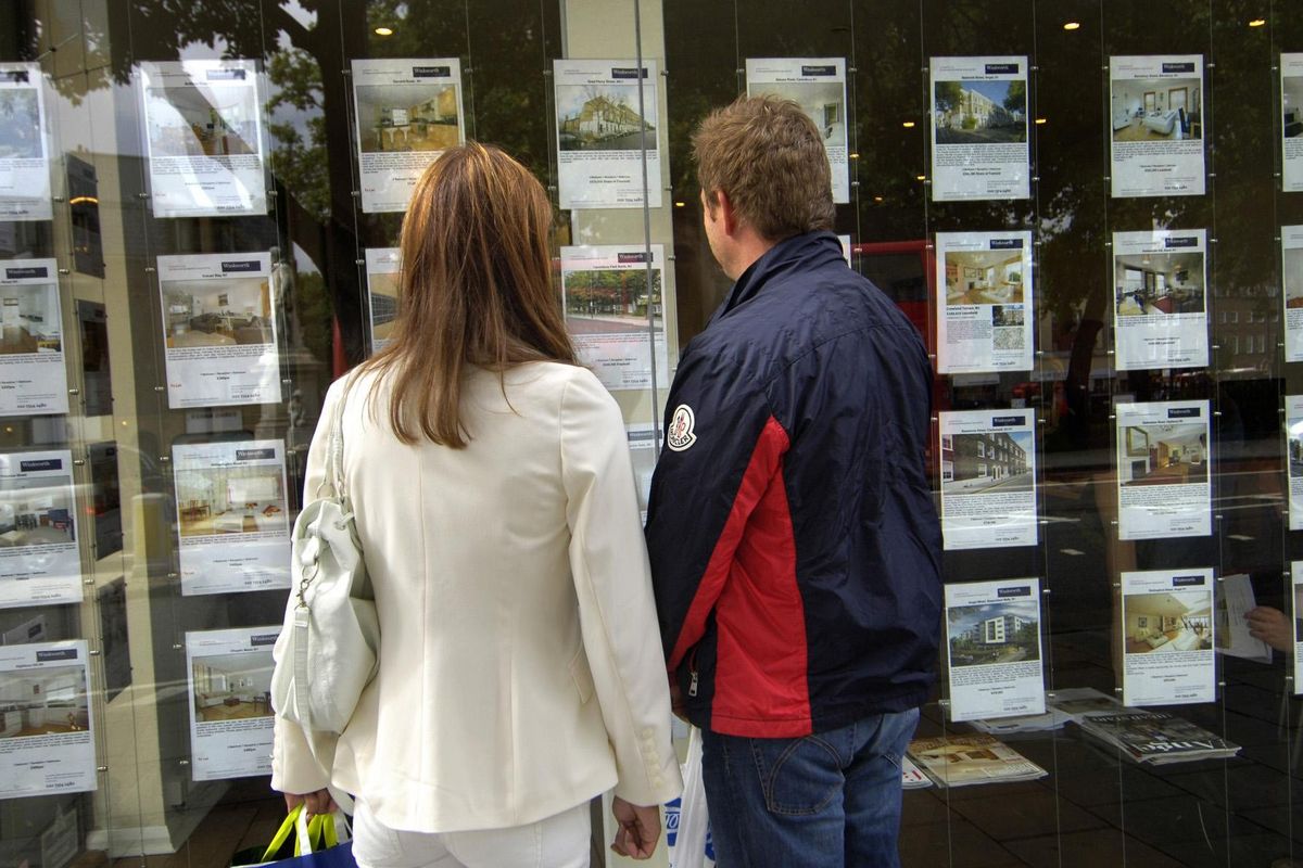 People looking at properties for sale in estate agent window