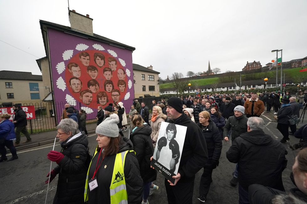 People pass a mural showing the 14 Bloody Sunday victims during a remembrance walk in Derry to mark the 50th anniversary of Bloody Sunday. Picture date: Sunday January 30, 2022.