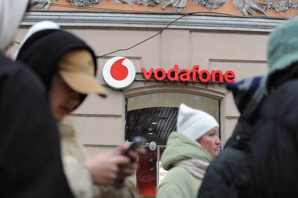 people pictured walking past a vodafone shop with the logo in-sight